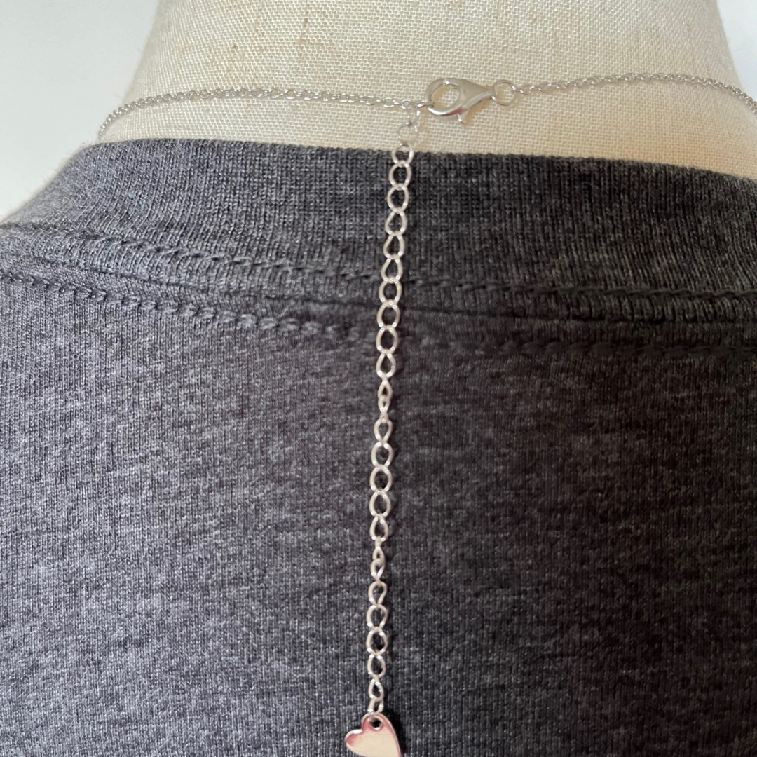 Clasp and extension shown from back of Evil eye necklace, shown with charcoal grey t-shirt