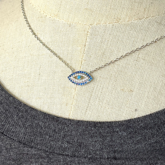 Evil eye necklace shown with charcoal grey t-shirt. Really close up.