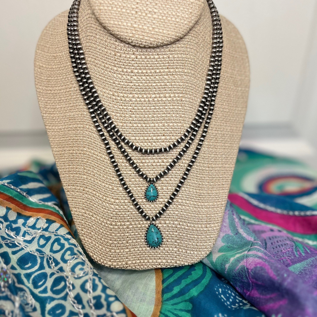 Multi Layered Teardrop Navajo Necklace - Turquoise Stones and Burnished Silver Beads.  Staged on Top of a Sarong.